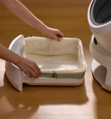 Petlibro automatic cat litter box with removable white tray and plastic liner being prepared on wooden floor